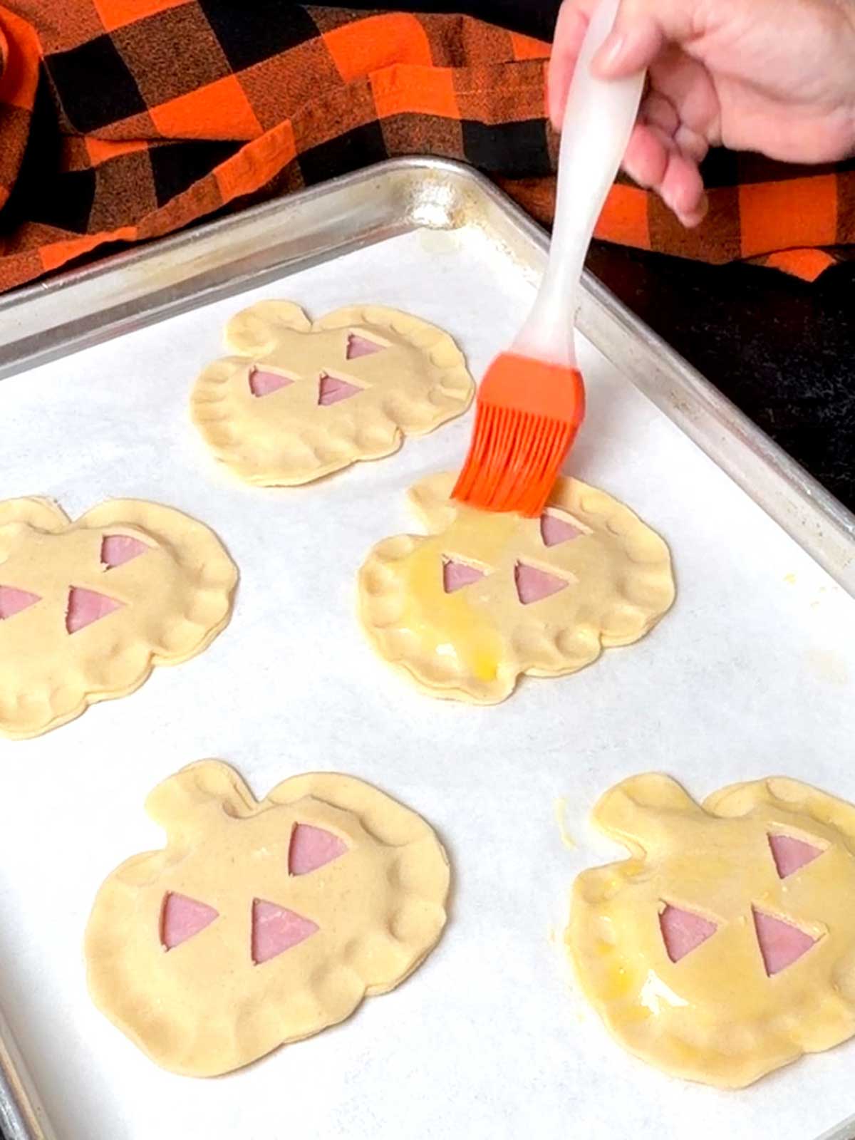 Brushing the ham and Swiss hand pies with egg wash.