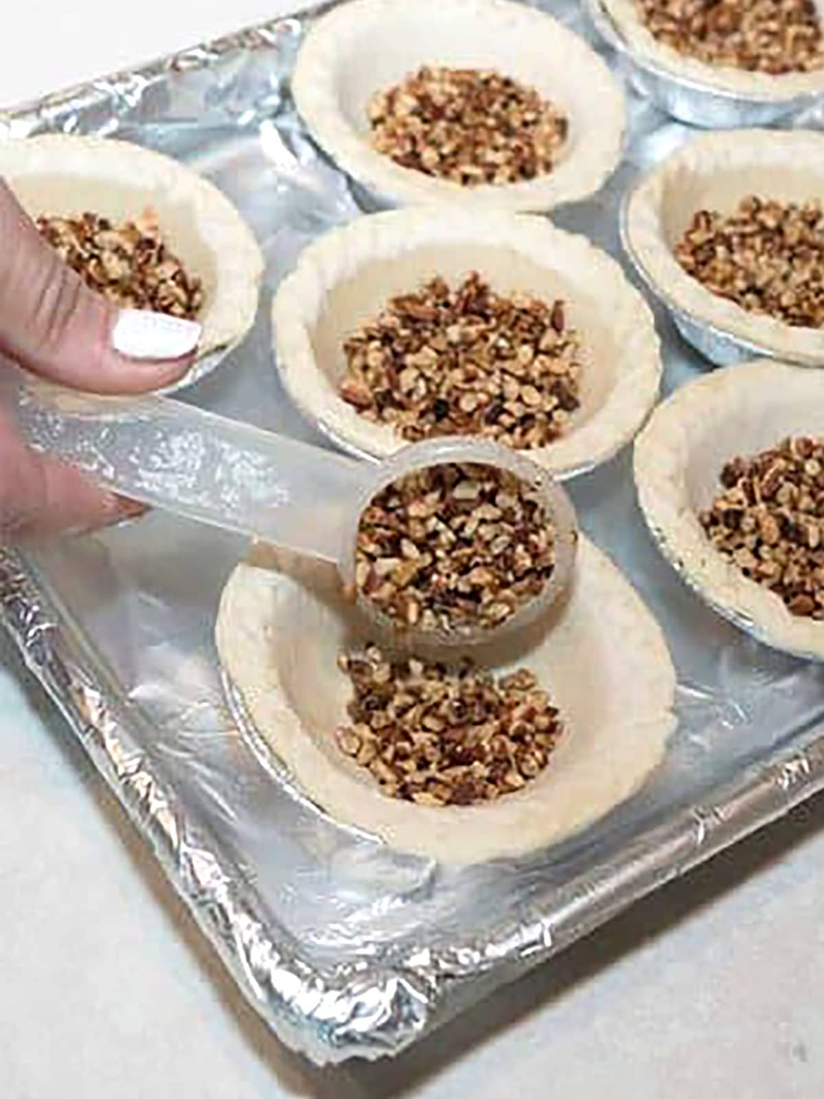 adding toasted pecans to mini pie shells