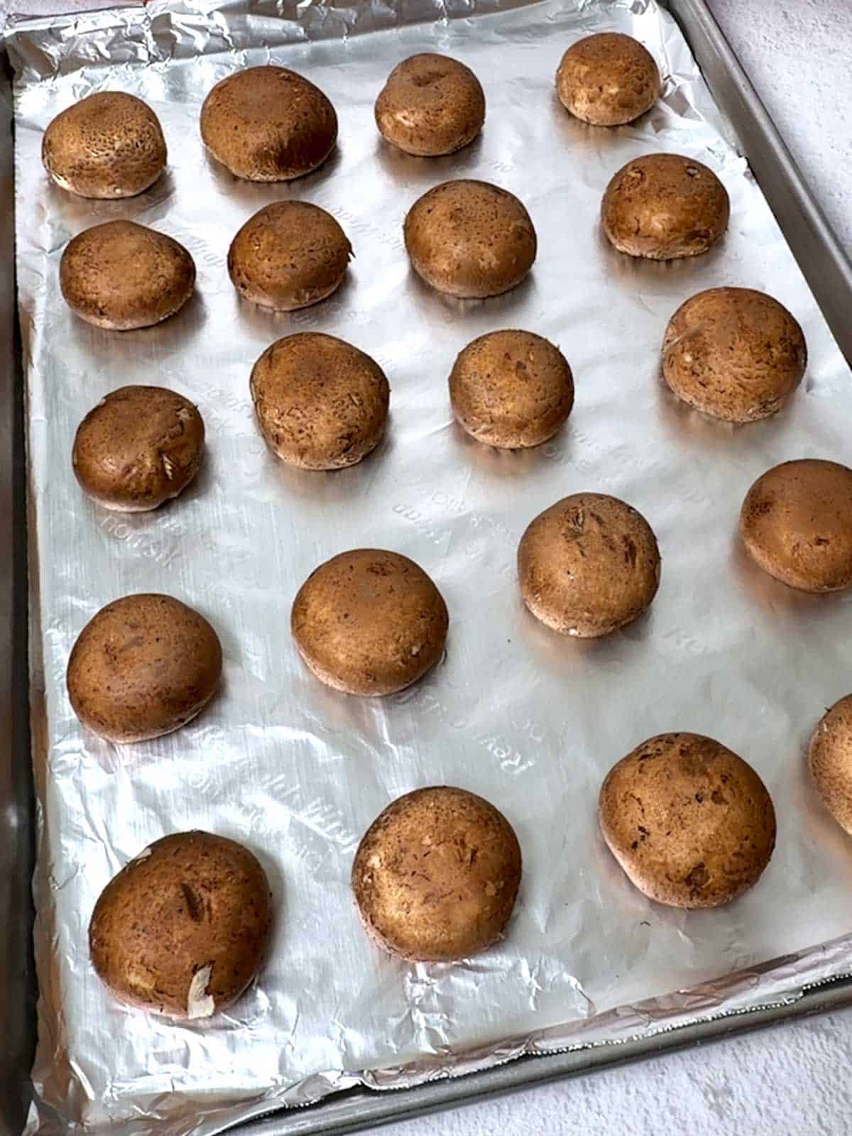 Mushrooms upside down on baking sheet.
