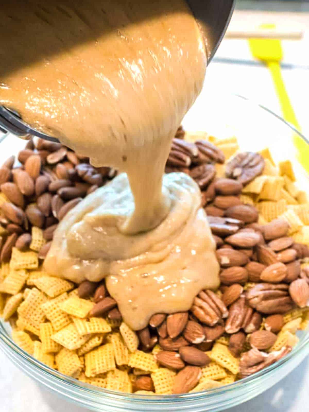 Pouring caramel over the cereal and nuts.