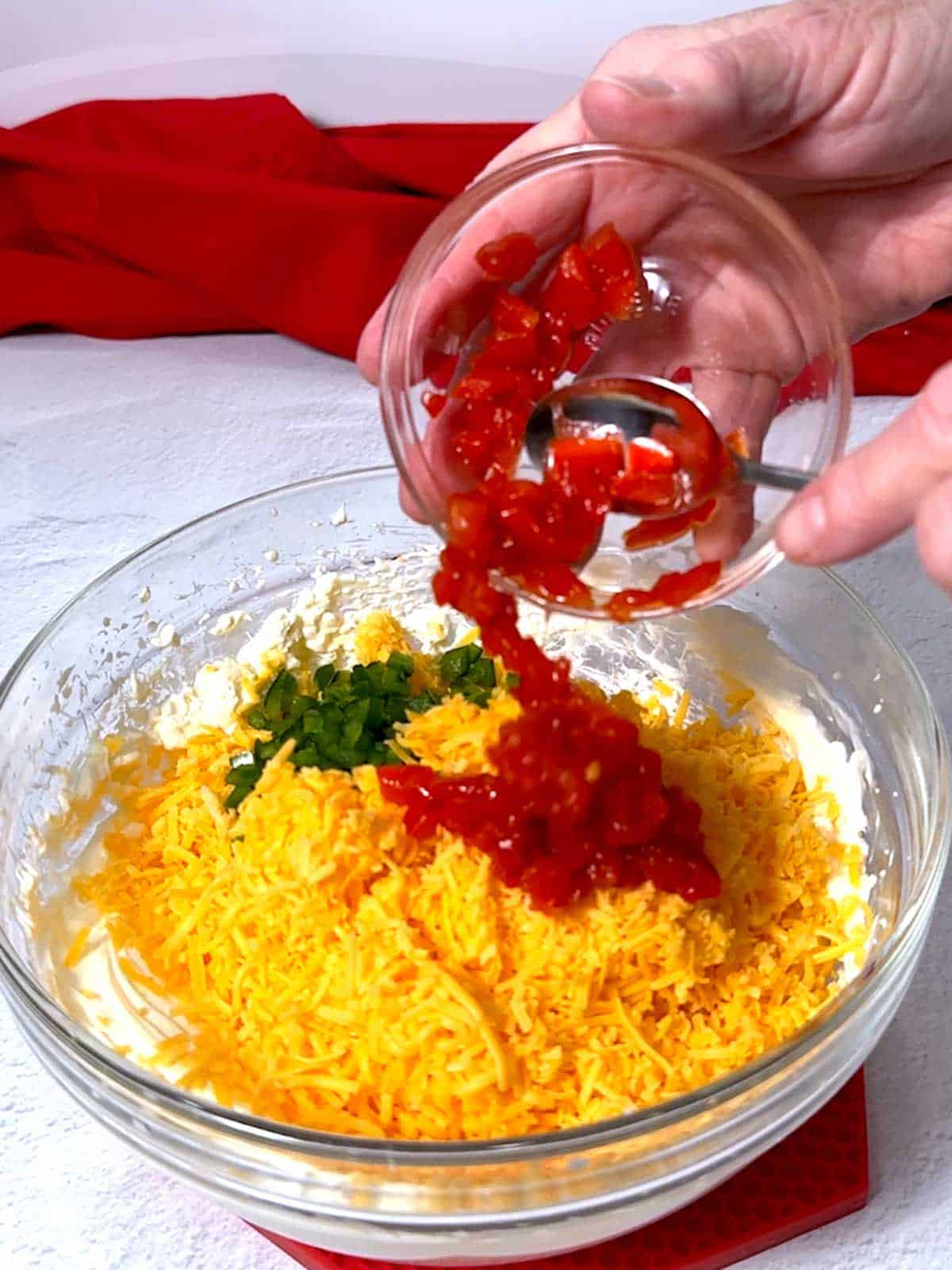 Adding pimentos to the remaining ingredients.