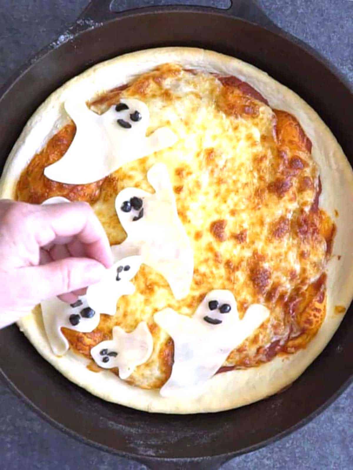 Placing the ghosts on the hot pizza.