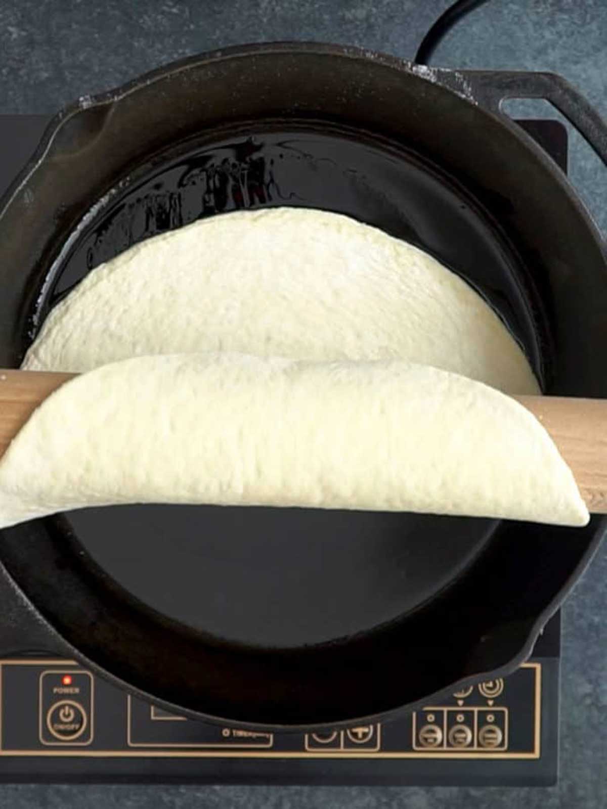 Transferring the pizza dough to the cast iron skillet.