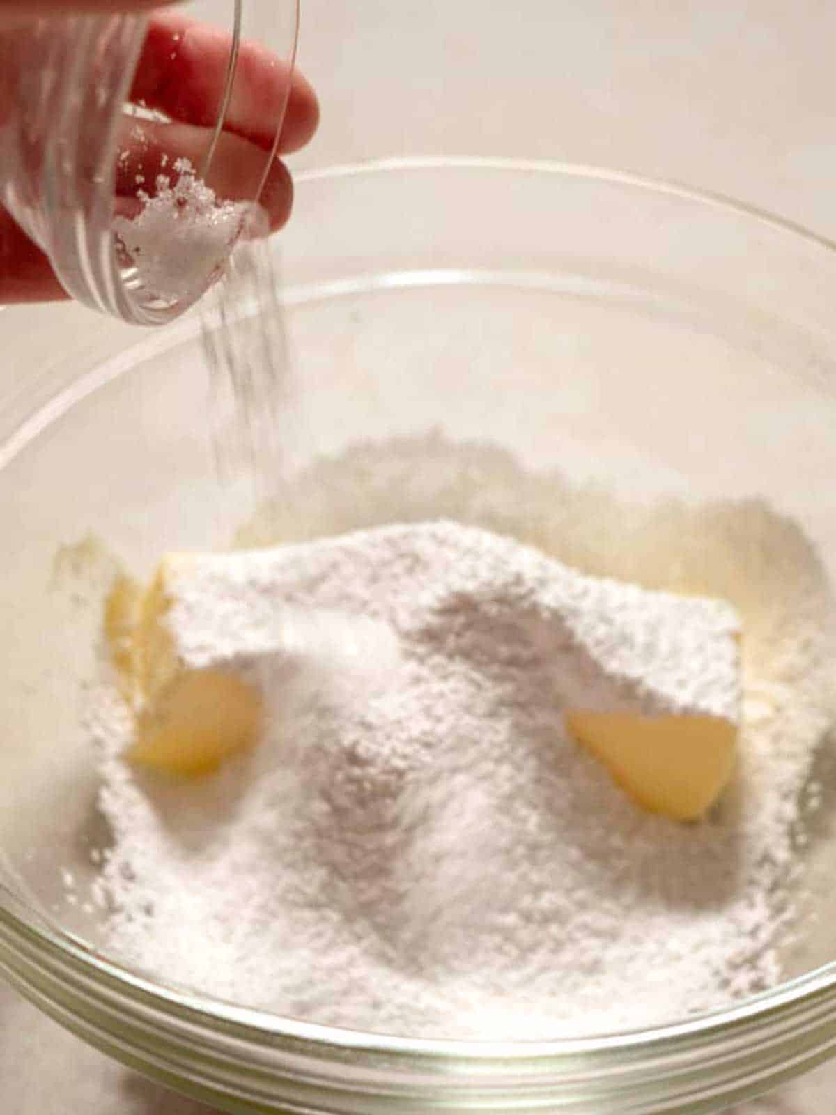 Adding salt to the butter and sugar.