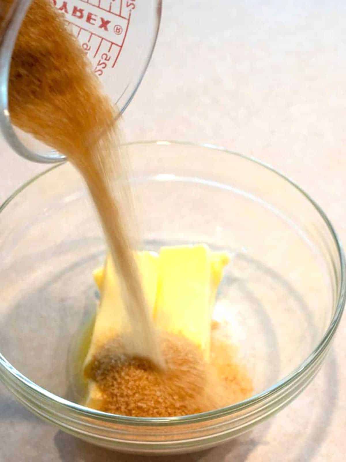 Adding turbinado sugar to butter in a medium bowl.