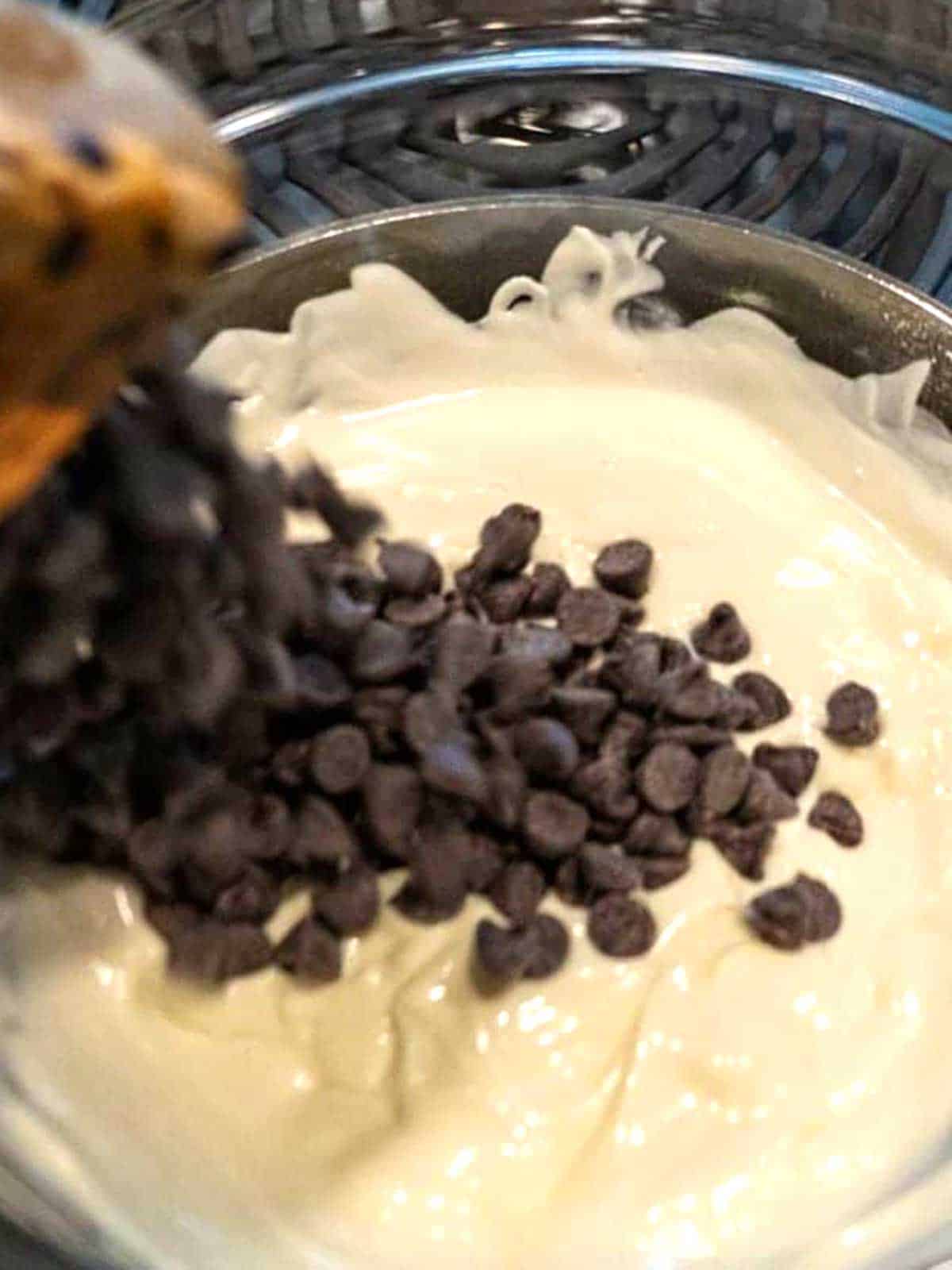 Adding chocolate chips to the melted white melting wafers.