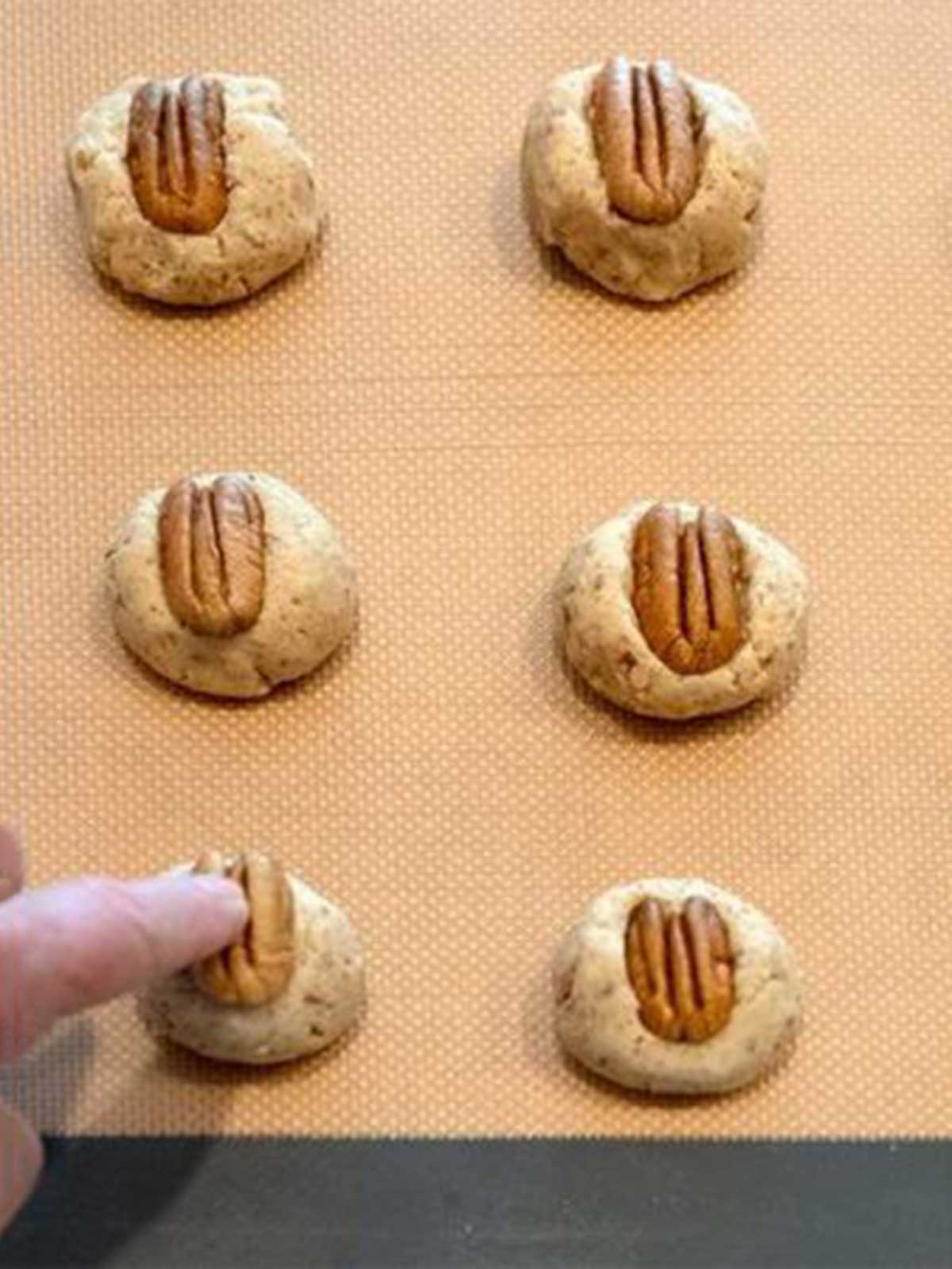 Pressing pecan into cookie dough.