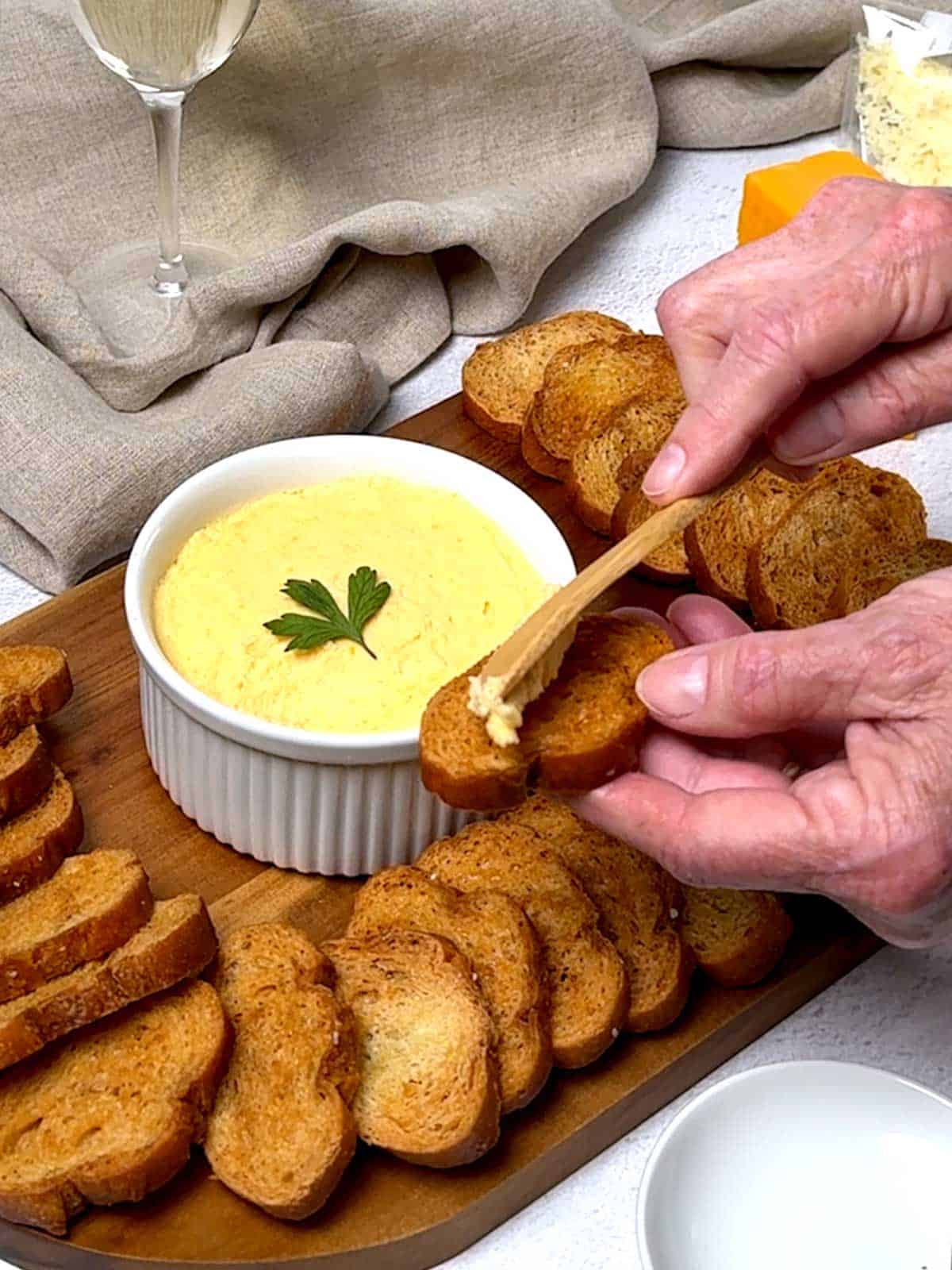 Spreading fromage fort on a piece of toasted sliced baguette.