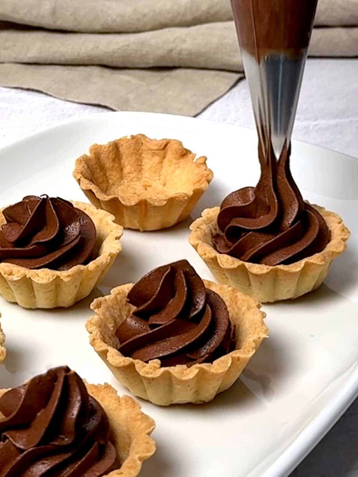 Whipped ganache piped into mini tart shell.
