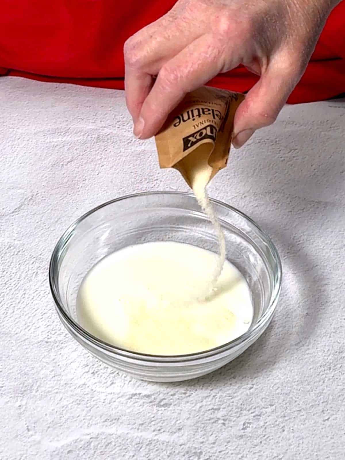 Adding gelatin to milk in a bowl.