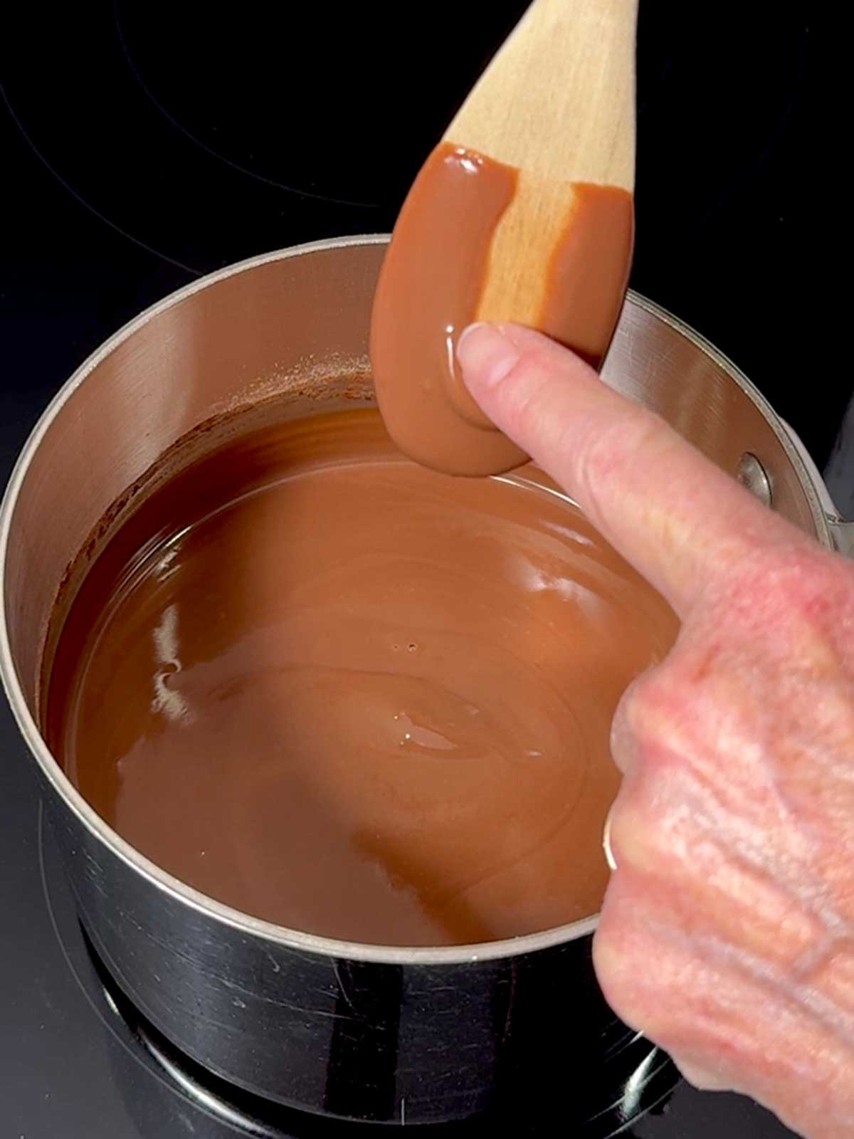 Chocolate blancmange mixture coating the back of a wooden spoon.
