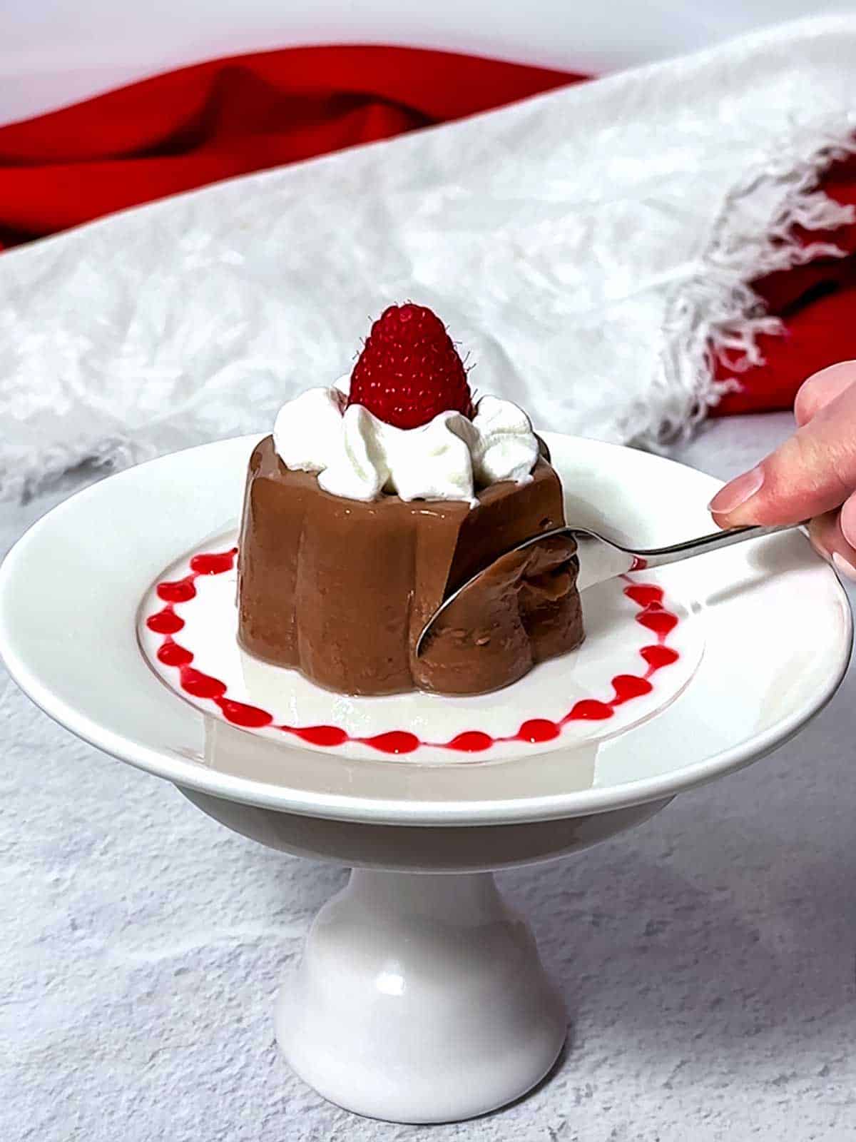 Using a spoon to eat the chocolte blancmange.