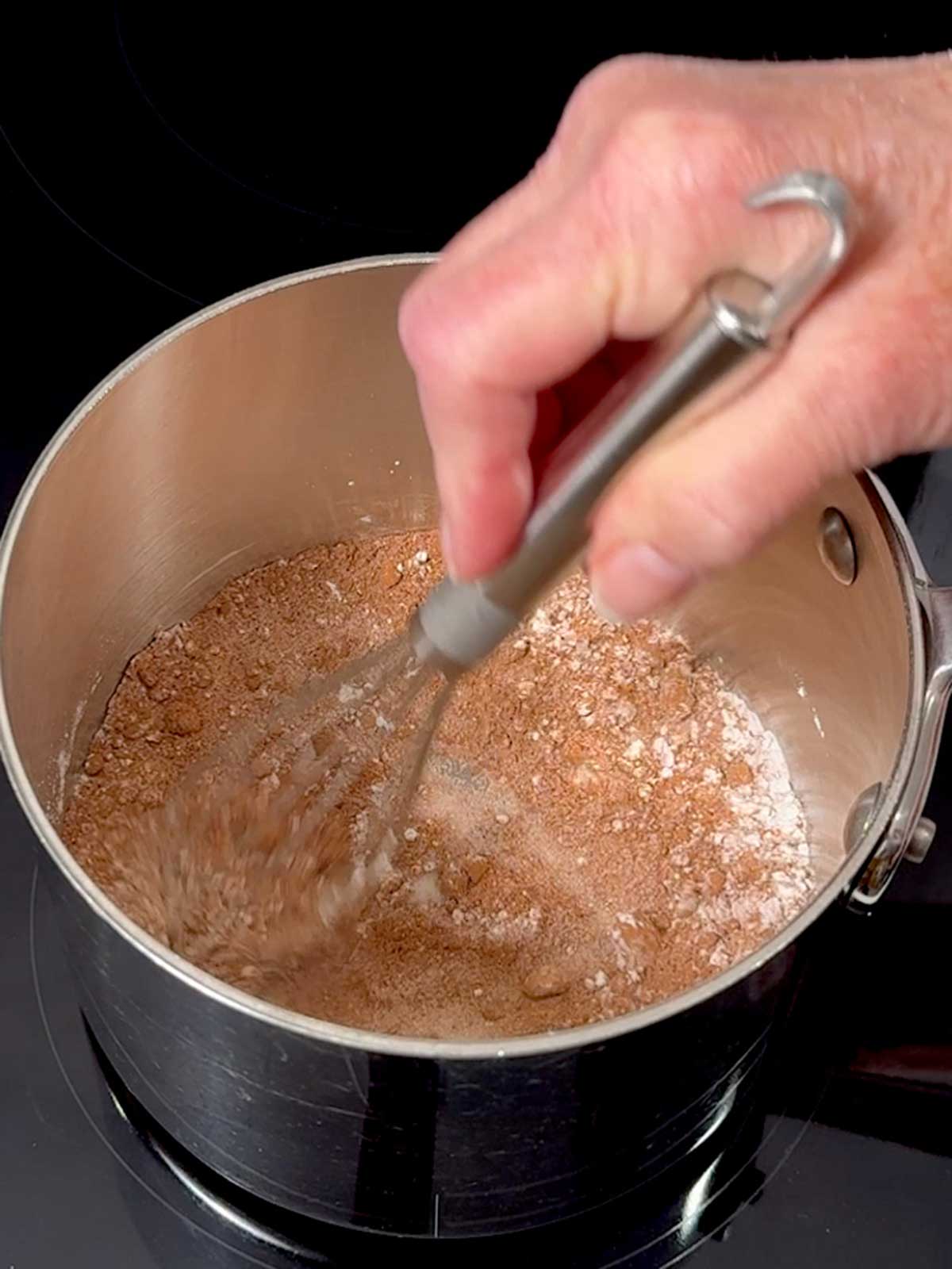 Whisking the sugar, cocoa, and cornstarch together in a saucepan.