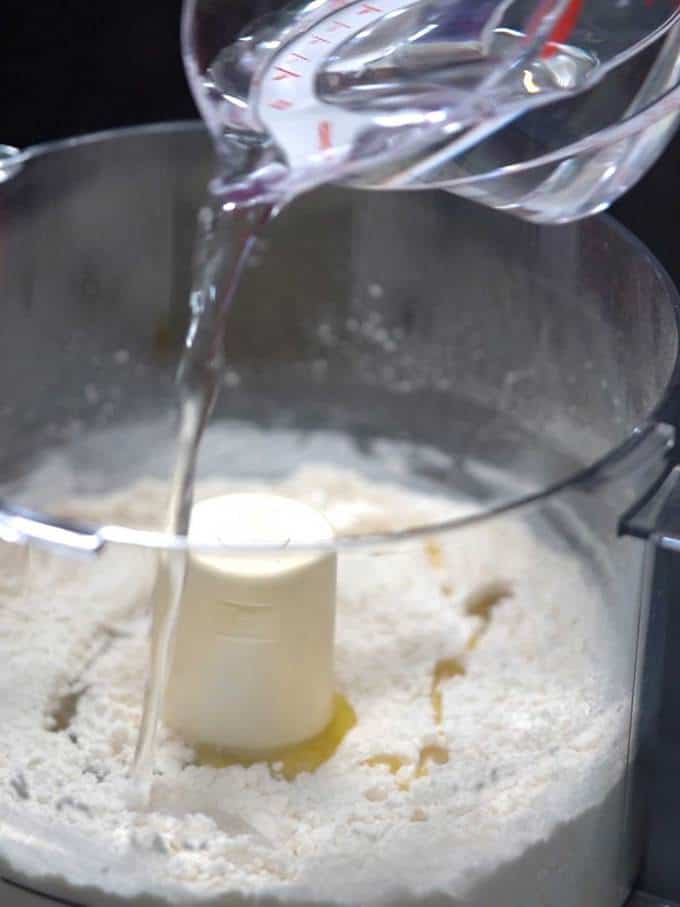 Adding water to flour to make pizza dough