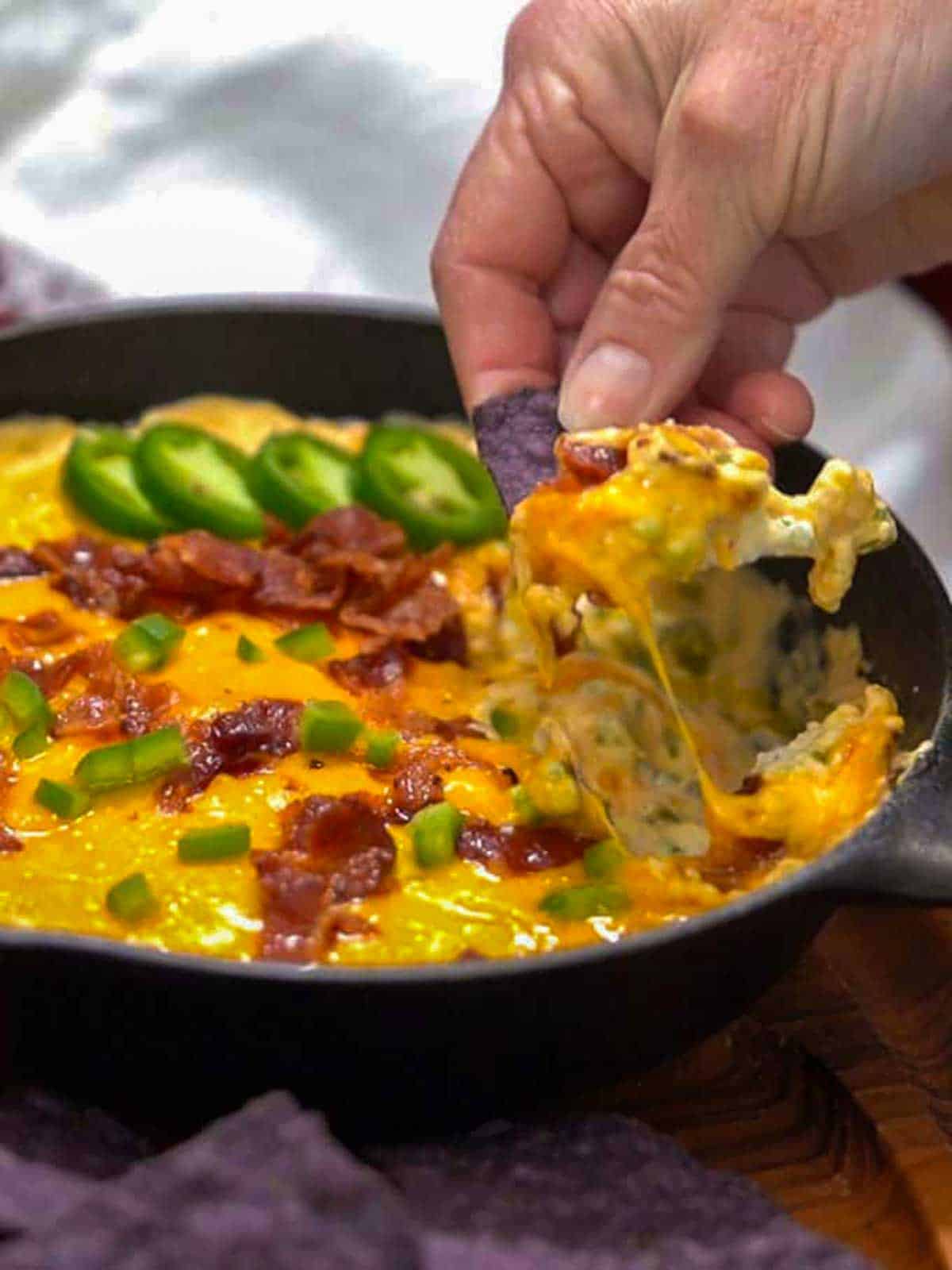 Scooping jalapeño popper dip with tortilla chips.
