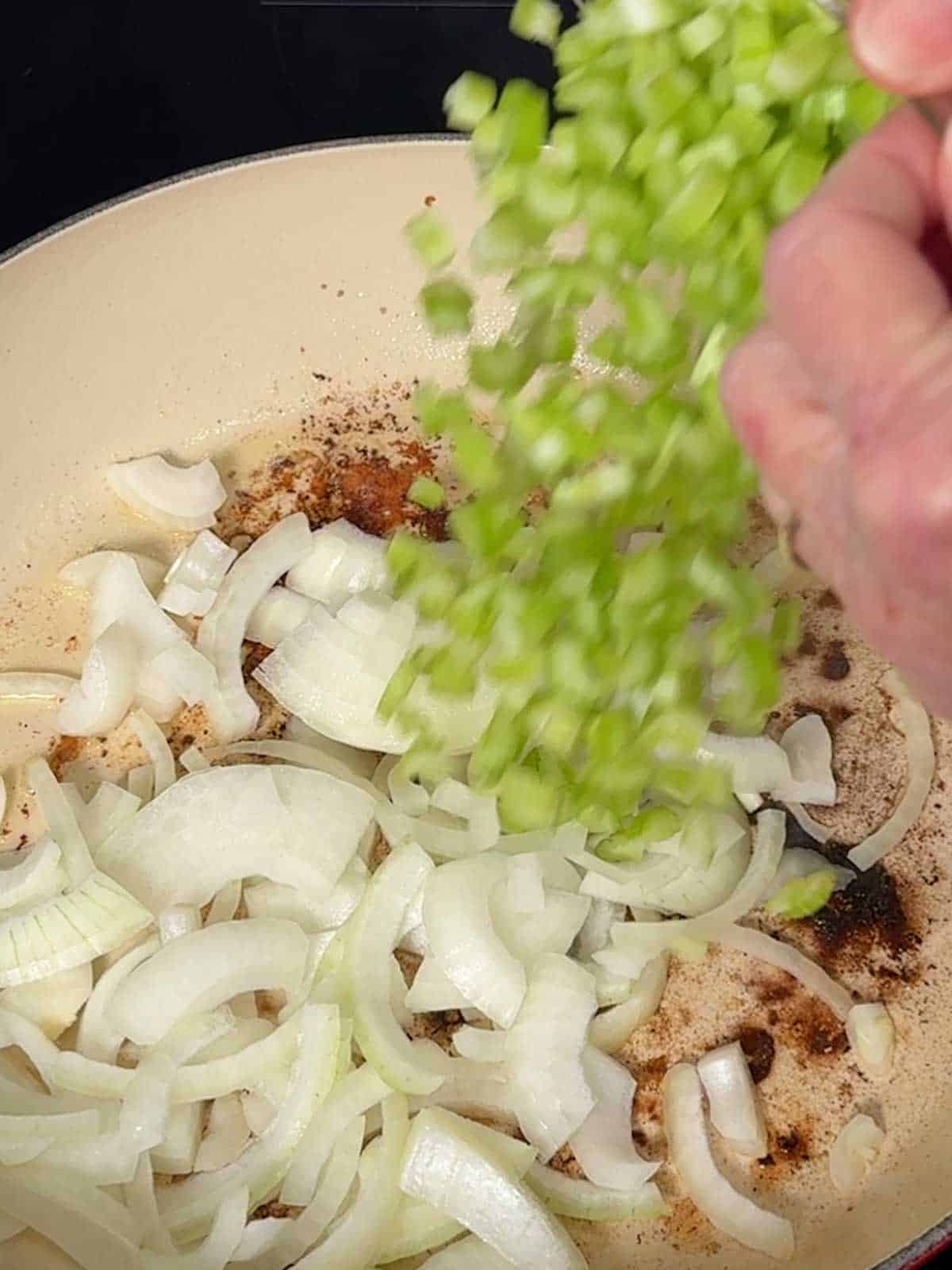 Adding celery to the Dutch oven.