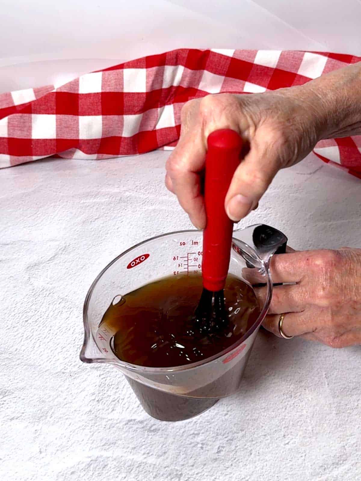 Whisking the beef broth, Worcestershire sauce, and tomato paste in a measuring cup.