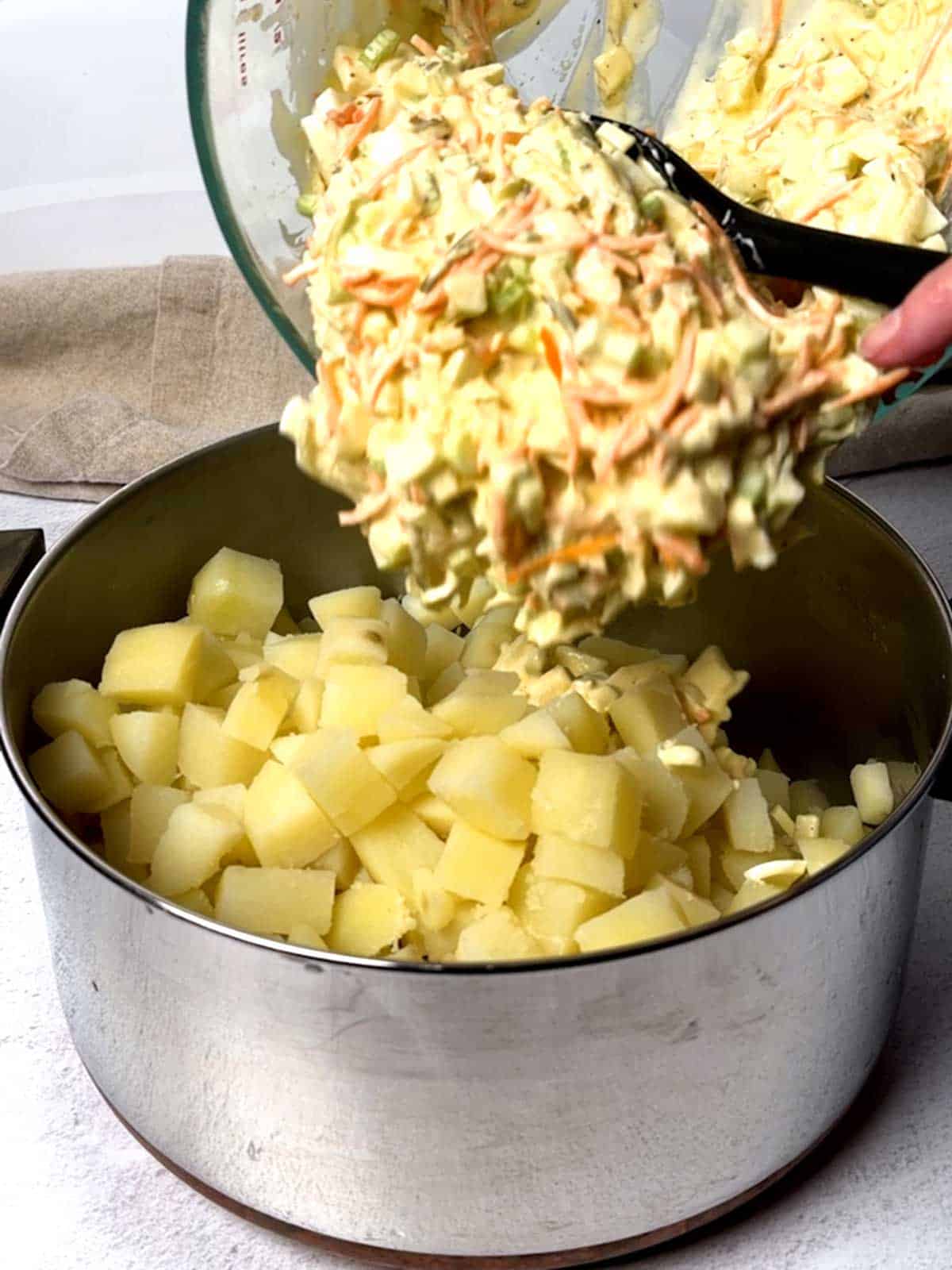 Adding the dressing to the cooked potatoes.