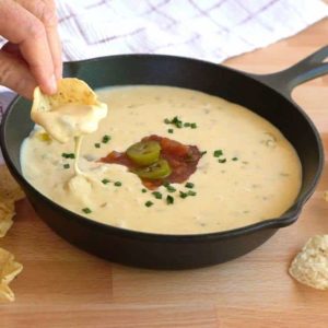 Dipping Tostidos Scoop in White Queso Dip