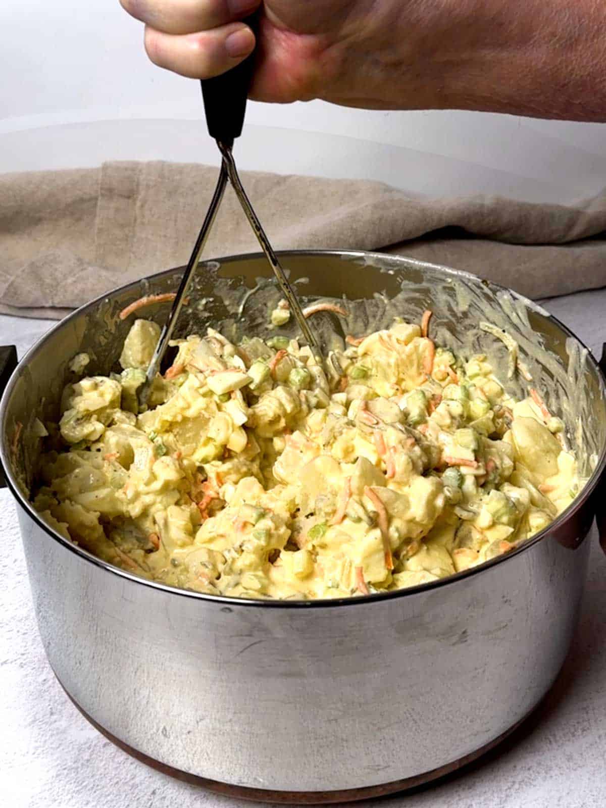 Using the potato masher to break up the potatoes.