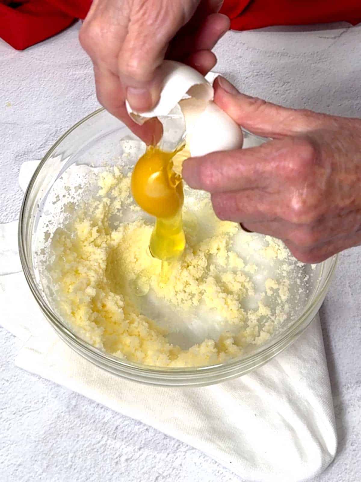 Adding an egg to the butter and sugar mixture.