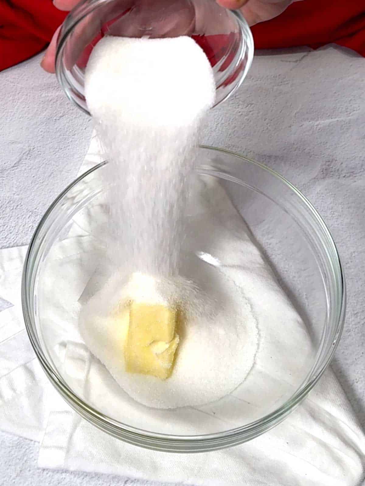 Adding sugar to the bowl with butter.