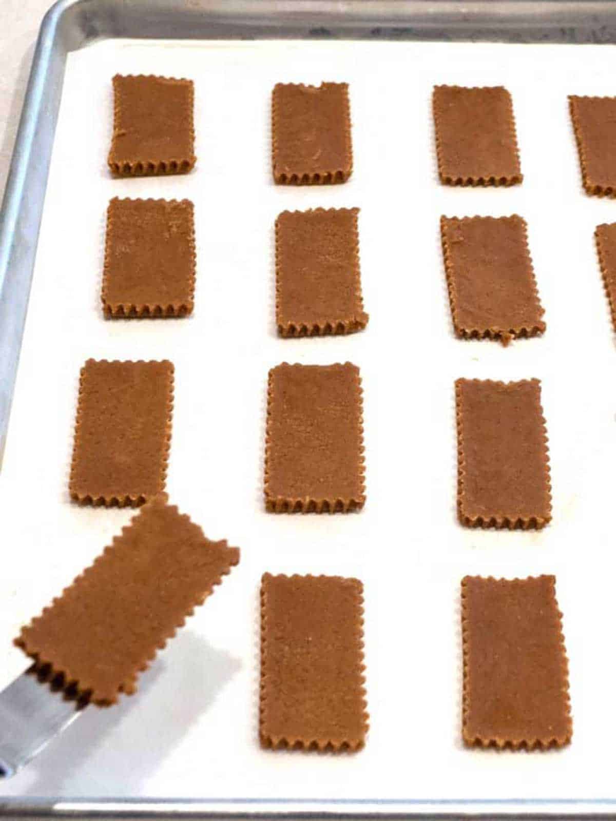 Placing the cut cookies on the baking sheet.