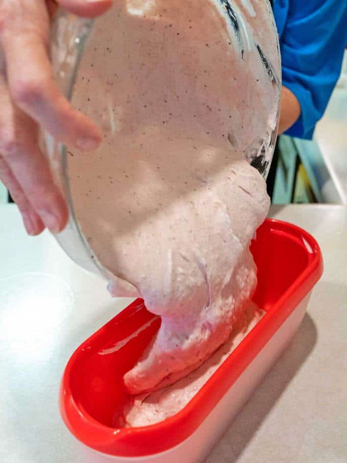 Pouring no-churn roasted strawberry ice cream mixture into freezer container