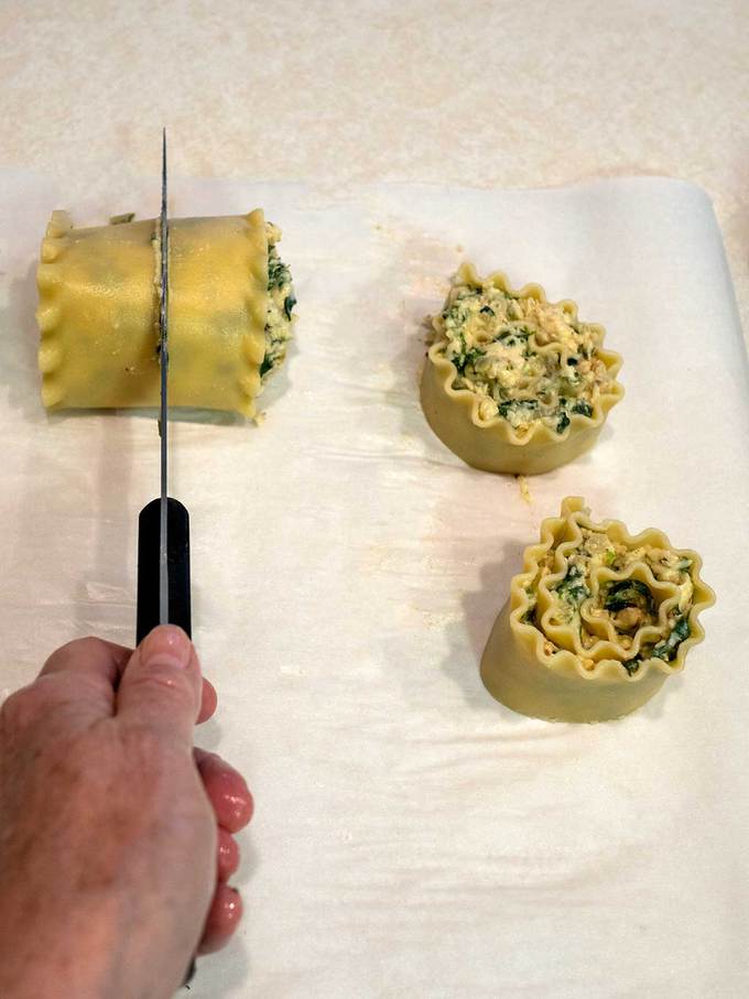 Cutting the lasagna rolls in half with a sharp knife