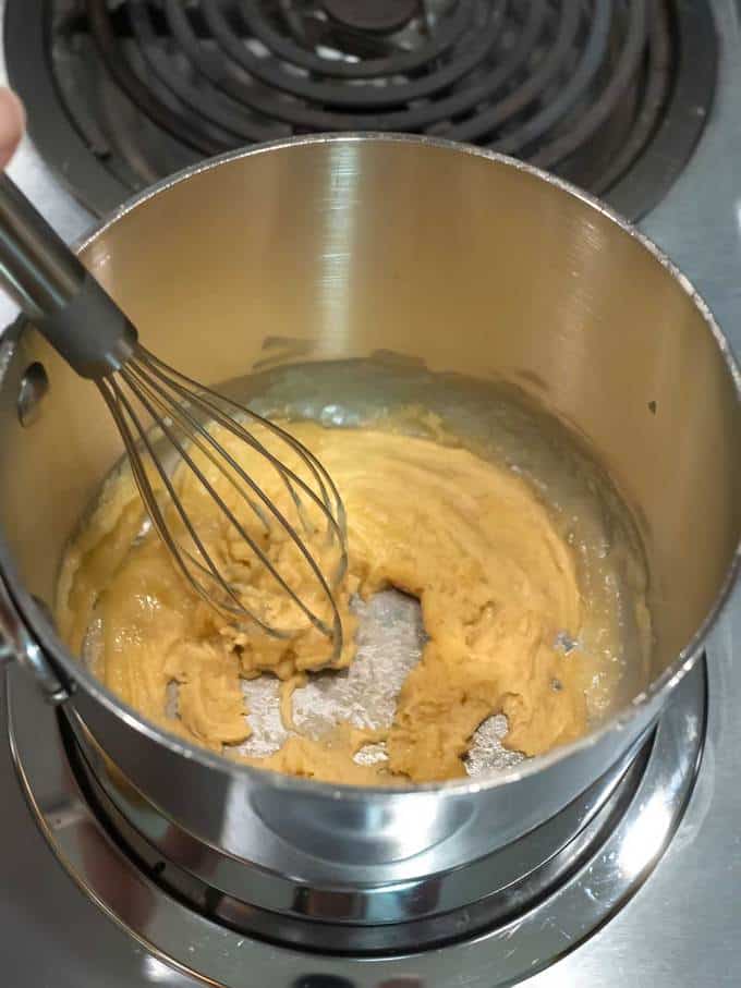Whisking butter flour and mustard in saucepan