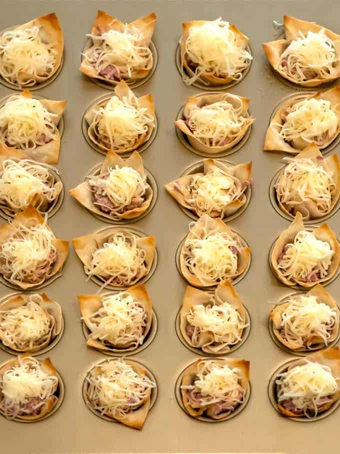 Topping Reuben Wonton cups with shredded Swiss cheese