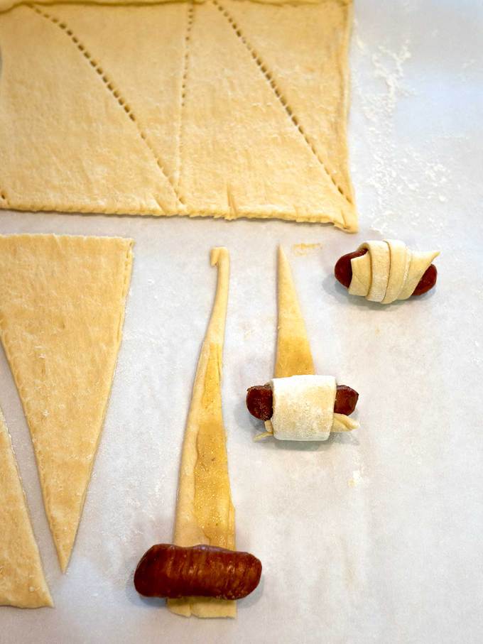 Rolling the crescent roll triangles around the Cocktail smokies 