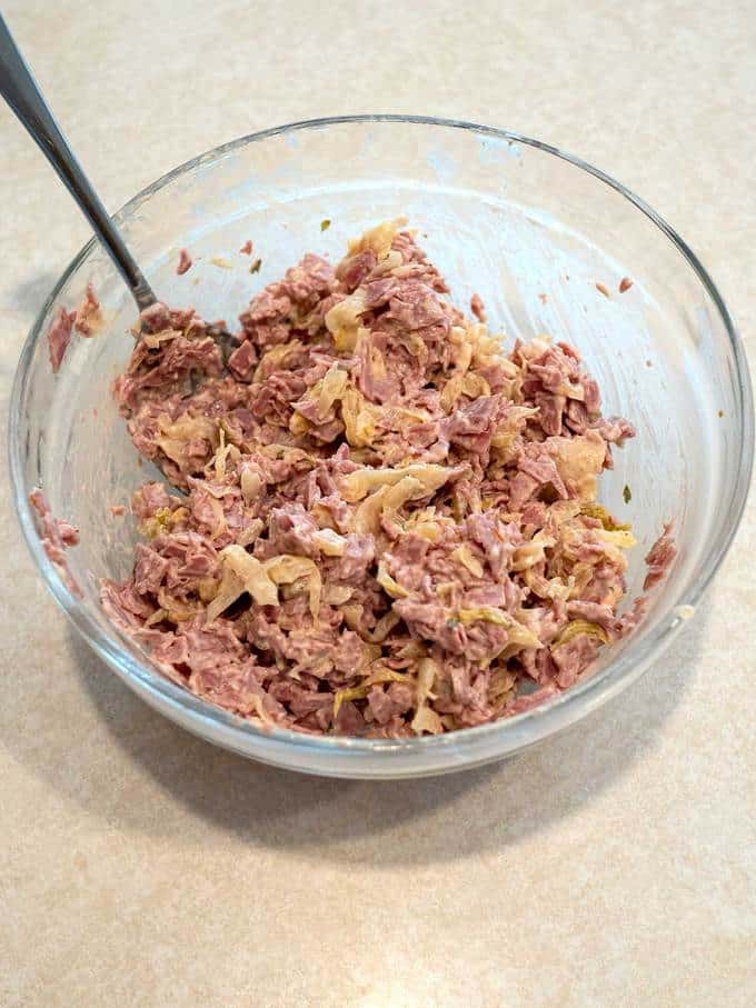 Corned beef, sauerkraut and Russian dressing mixed together in bowl.
