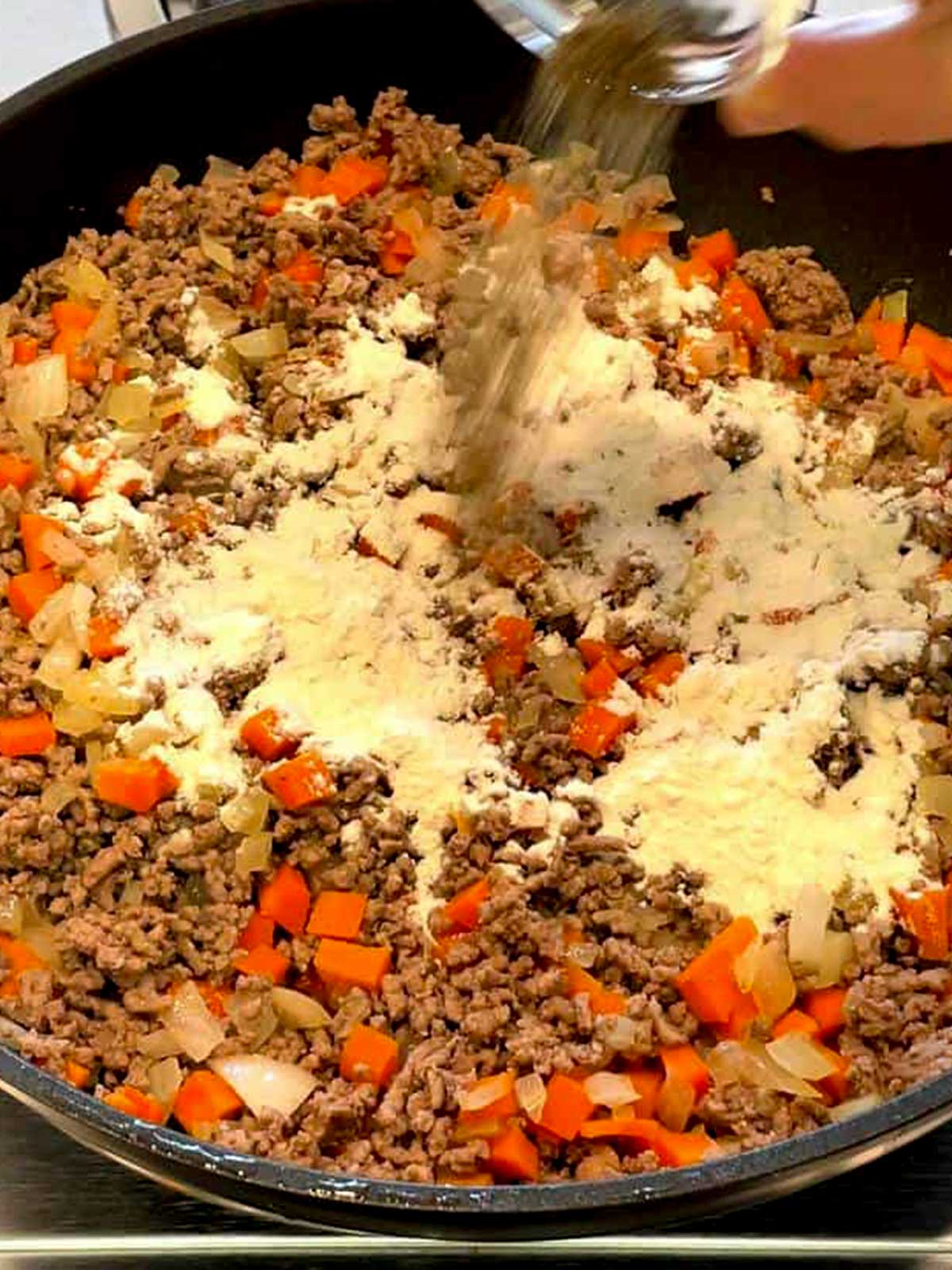 Adding pepper to the cottage pie mixture.