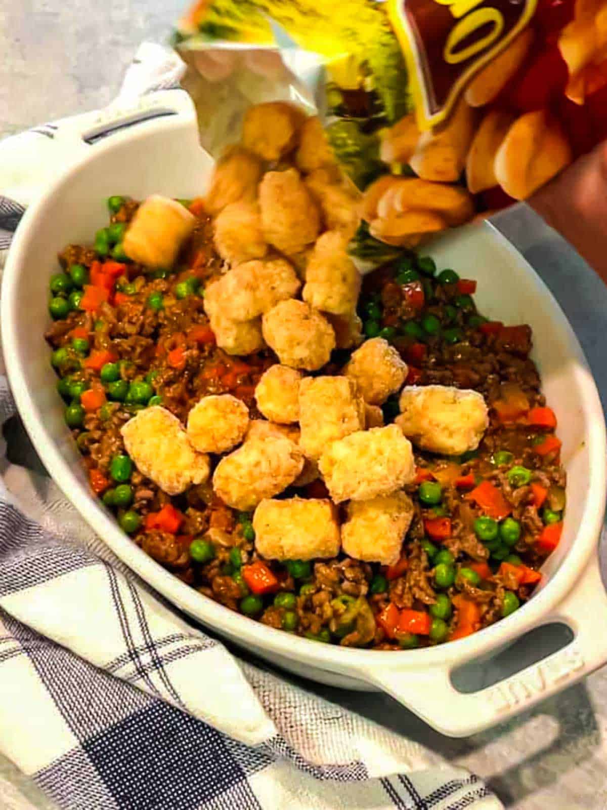 Adding tater tots to the cottage pie.