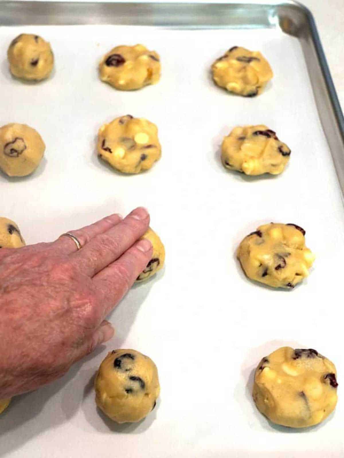 Flattening cookie dough with damp hand.