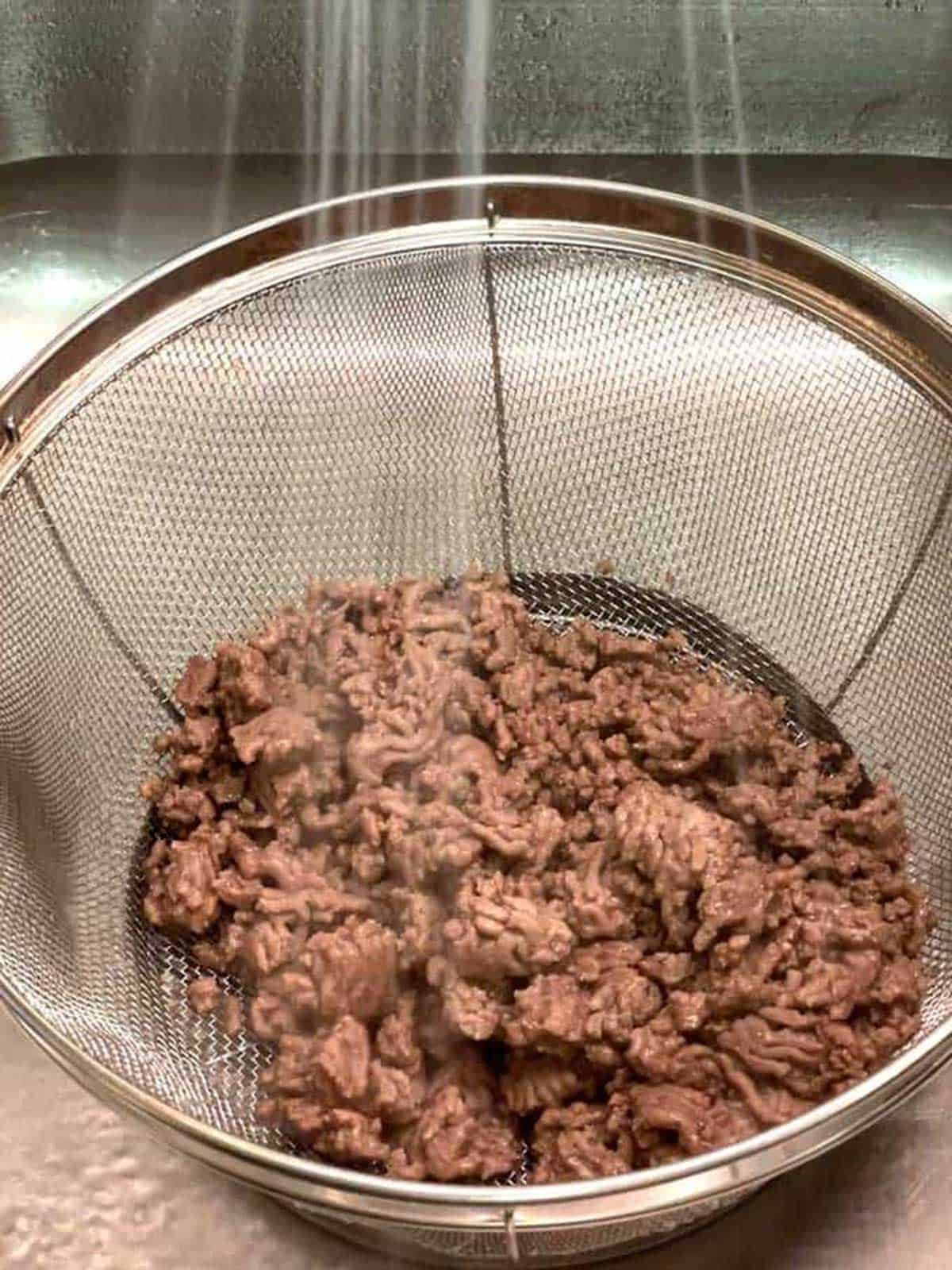 Rinsing the ground beef in a colander.
