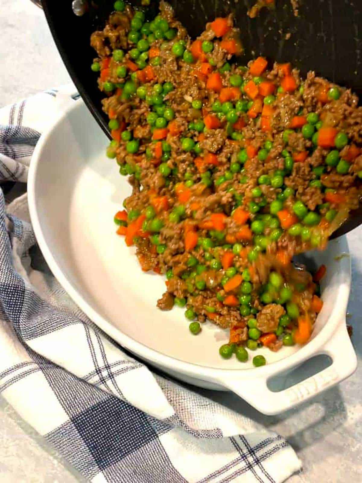 Transferring the cottage pie mixture to a casserole dish.