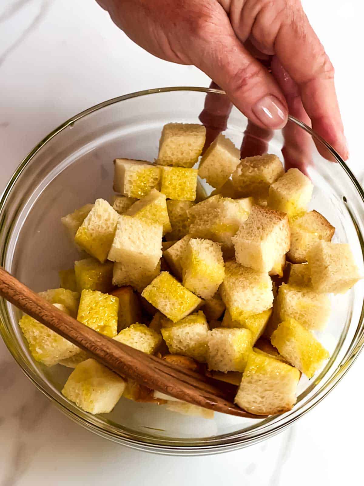 Coating bread cubes with infused olive oil.
