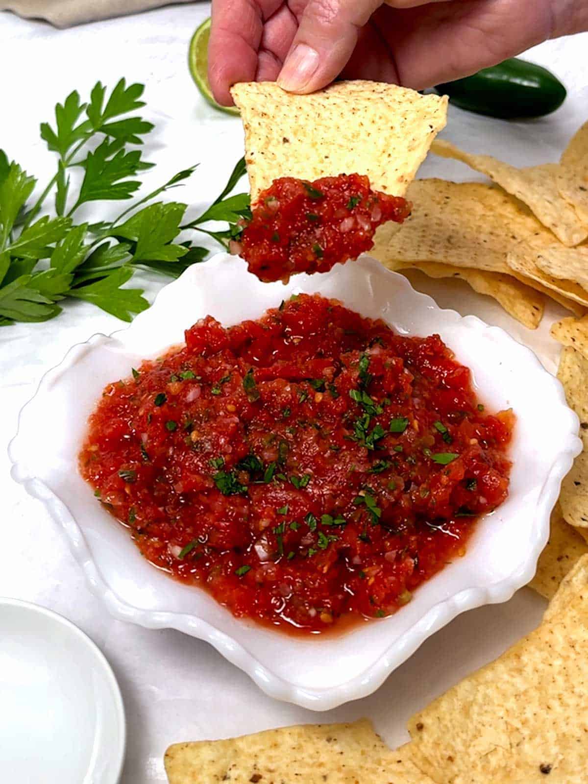 Dipping the tortilla chip in the salsa.