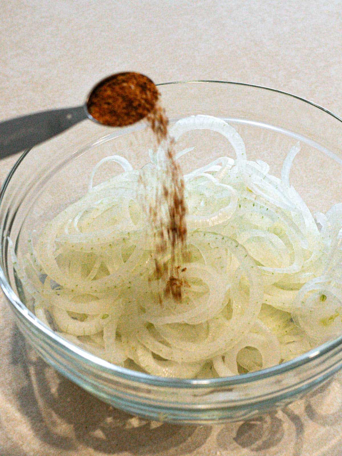Adding cajun seasoning to onions.