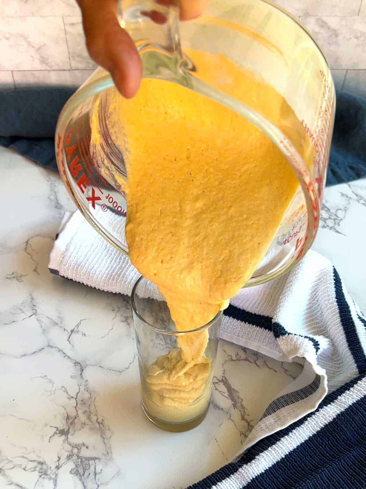Pouring batter into a tall glass.