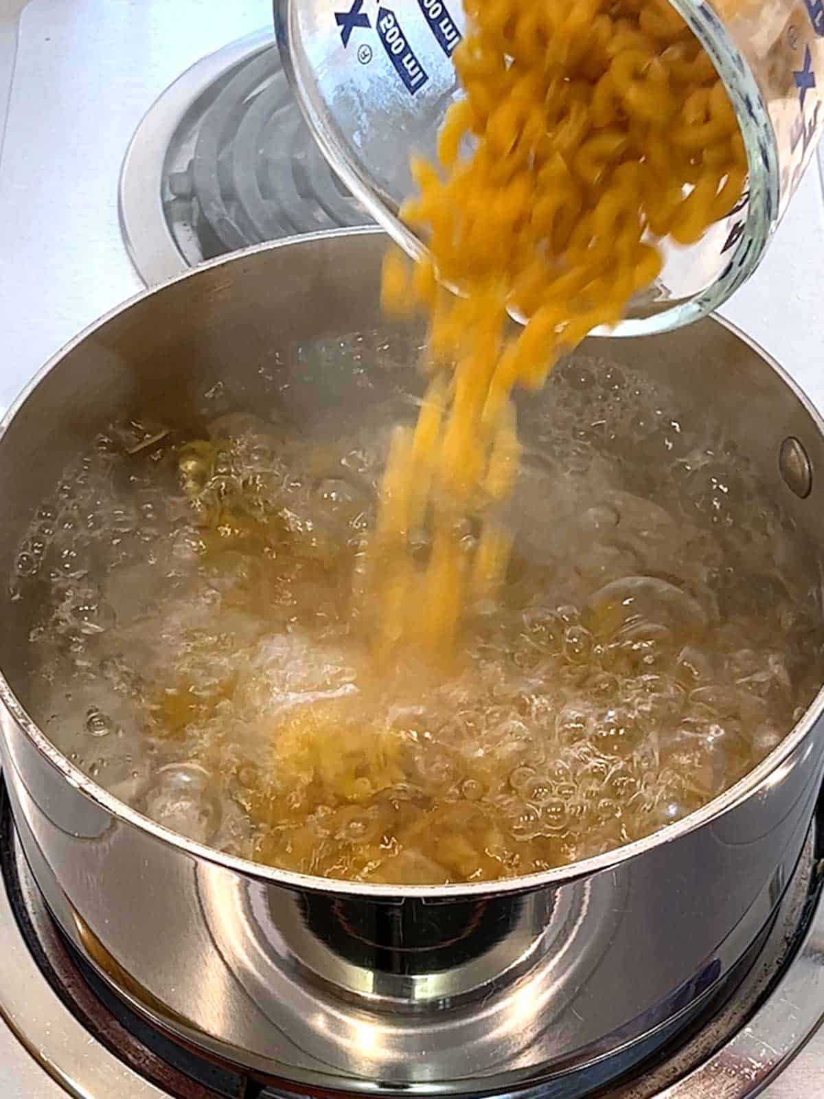 Adding macaroni to boiling salted water.