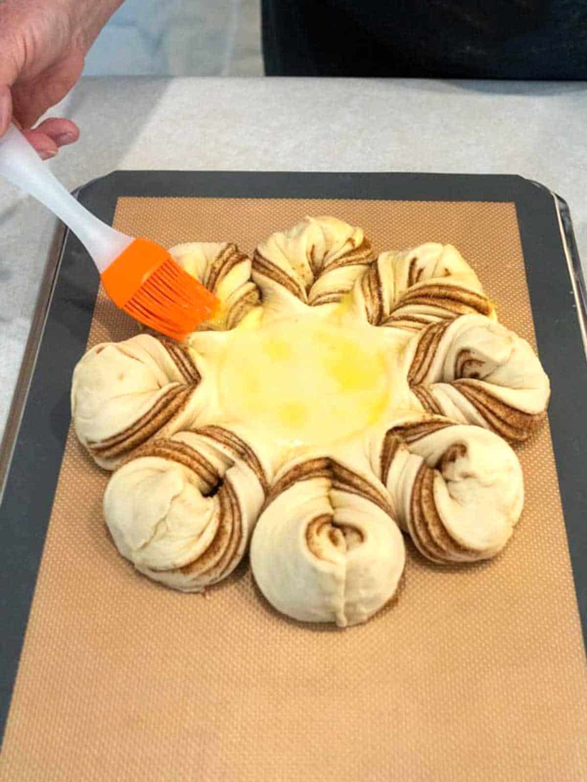 Brushing the snowflake bread with an egg wash.
