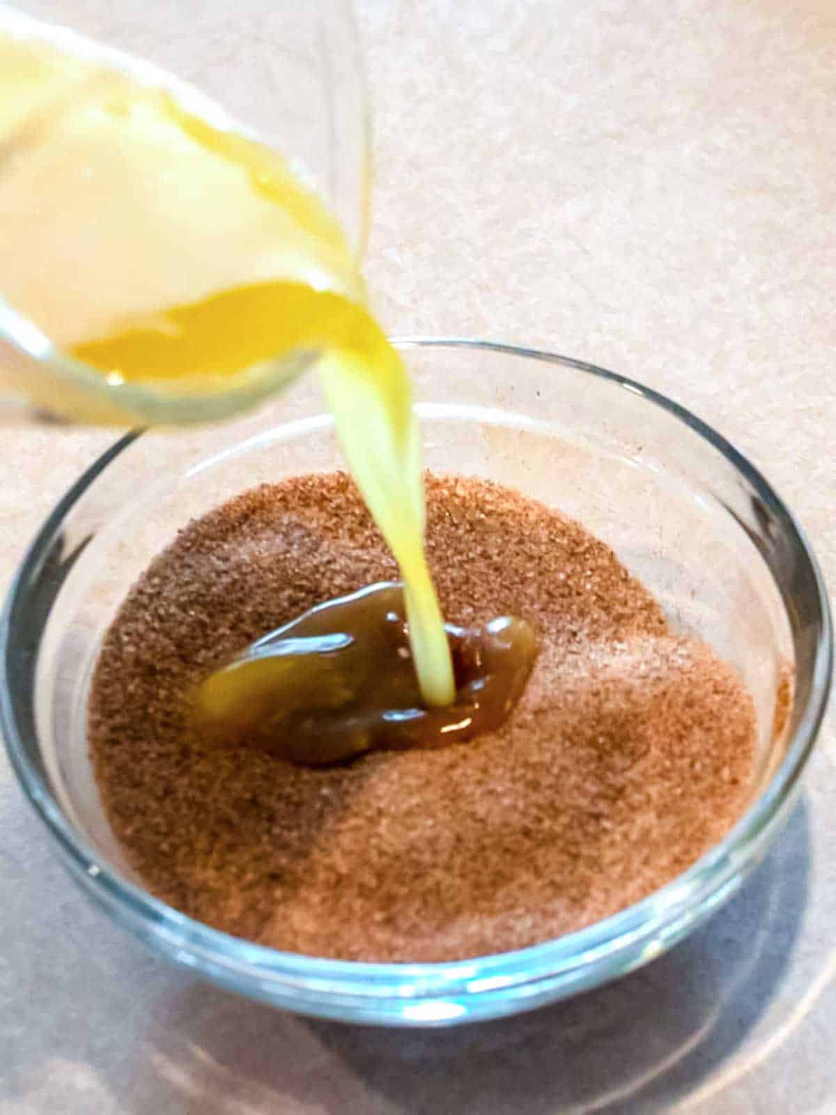Pouring melted butter into sugar and cinnamon mixture.