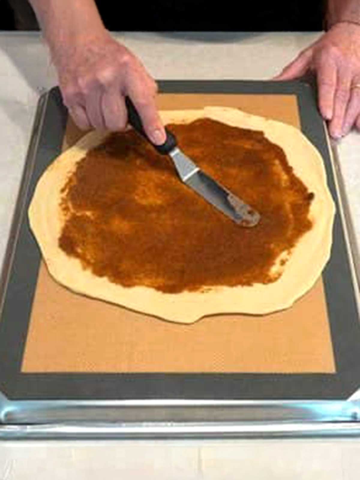 Spreading the sugar-cinnamon filling over the dough circle.