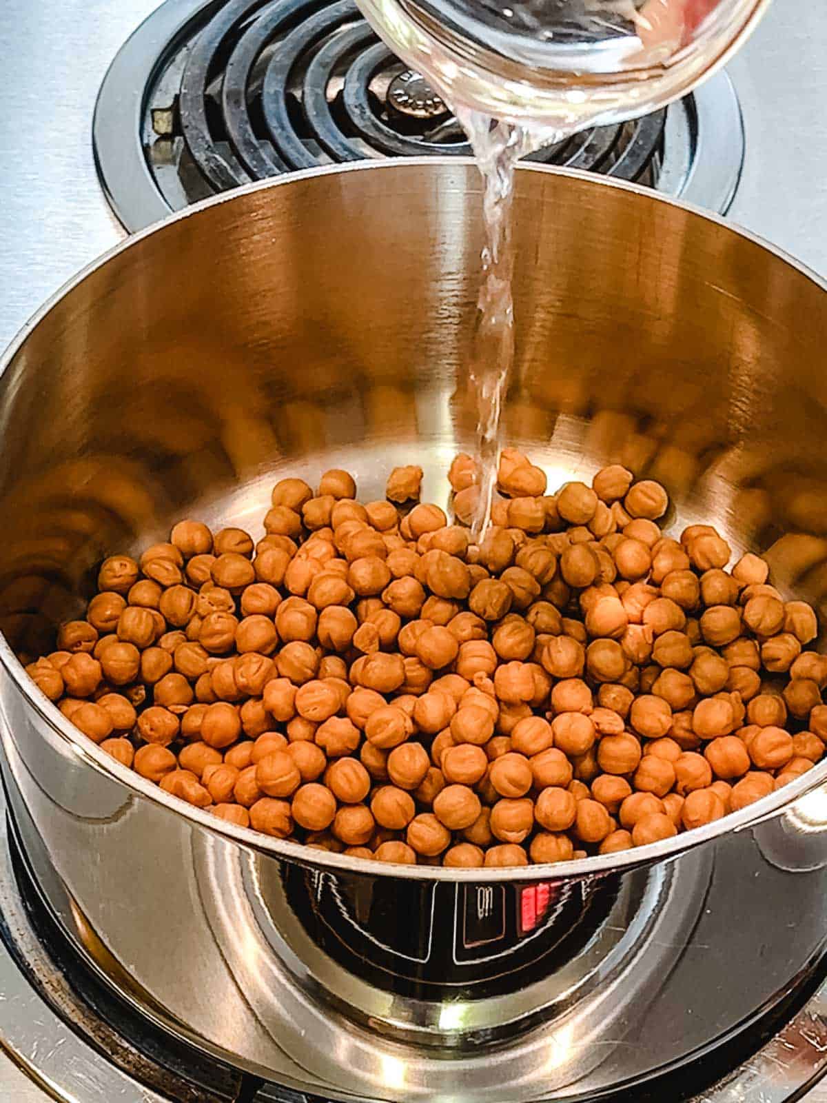 Adding water to caramel bits in large saucepan.