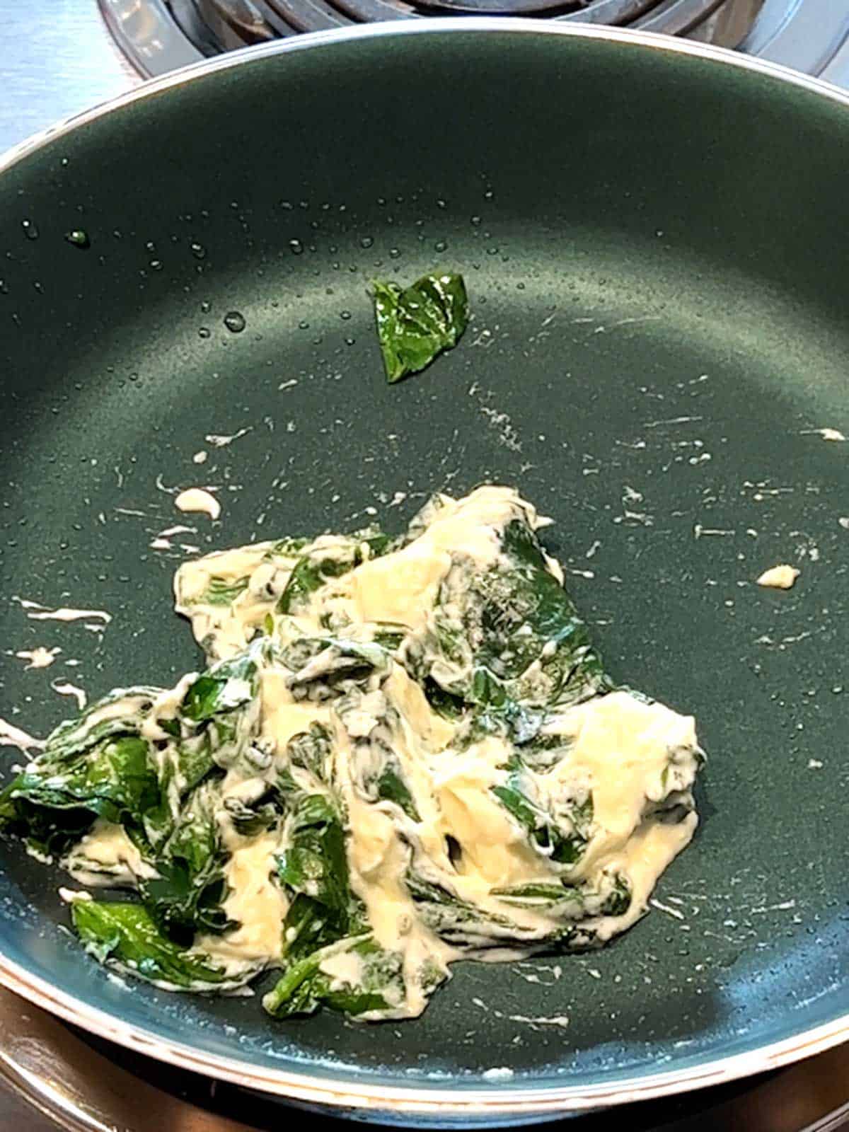 Boursin cheese and spinach combined in skillet.