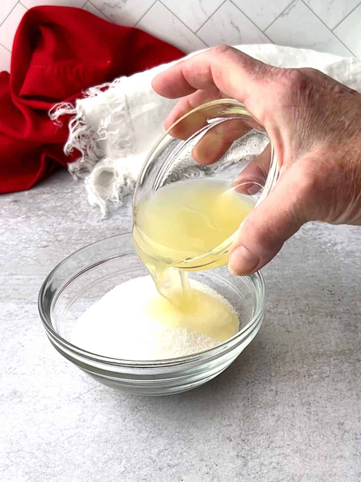 Pouring lemon juice on granulated sugar for lemon syrup.