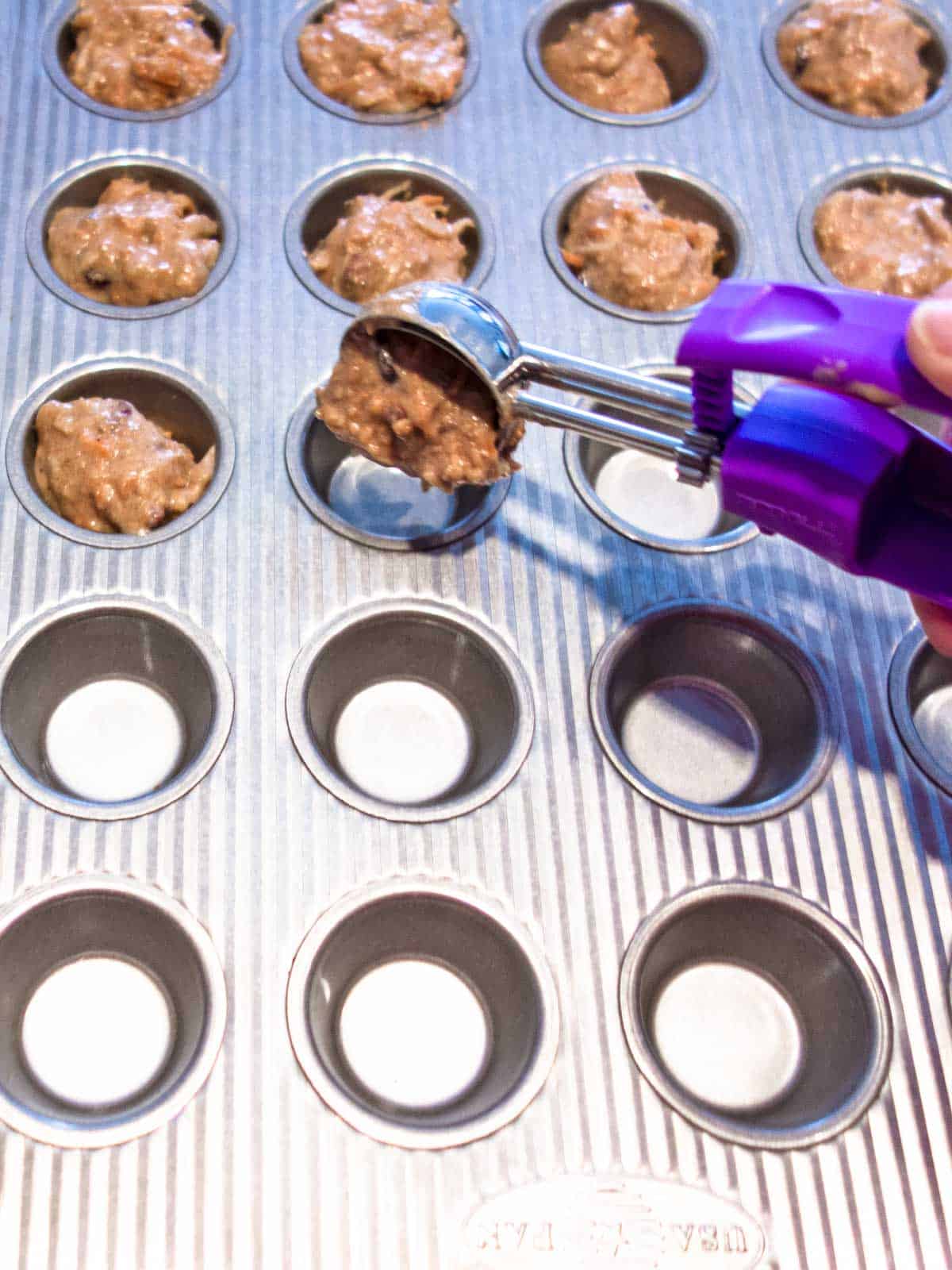 Adding batter to cups of mini-muffin pan.